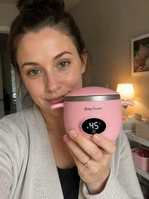 Une maman tient son Babycozidoo rose dans son salon en souriant