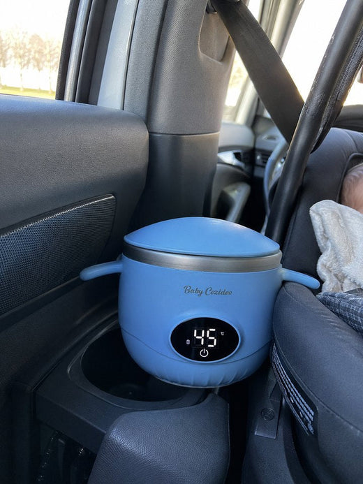 Un Babycozidoo bleu posé dans la console d'une voiture, bébé installé dans son siège auto à l'arrière