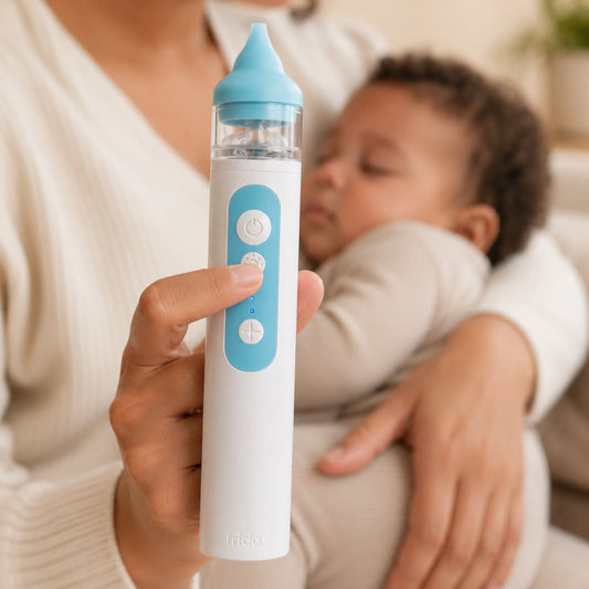 Mouche-bébé électrique NoseFrida tenu en main près d'un bébé endormi
