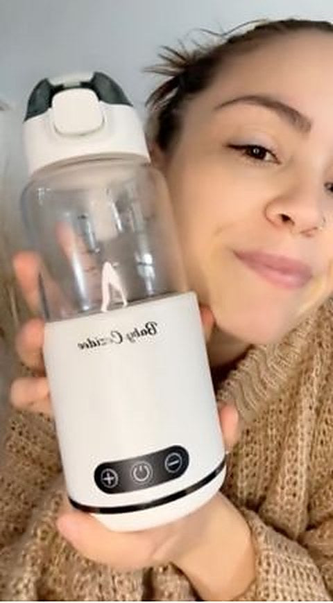 Une maman tient contre elle son chauffe-biberon sans fil Babycozidoo rempli de lait