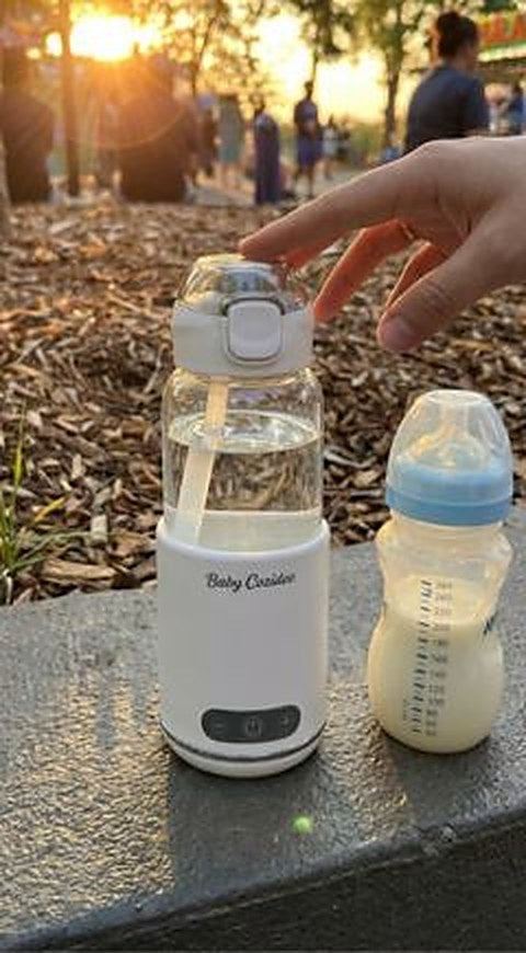 Le chauffe-biberon sans fil Babycozidoo et un biberon posés sur un muret dans un parc au coucher du soleil