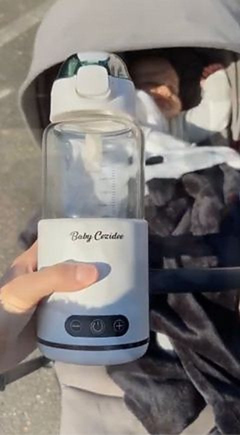 Une main appuie sur le bouton du chauffe-biberon Babycozidoo près de la poussette de bébé