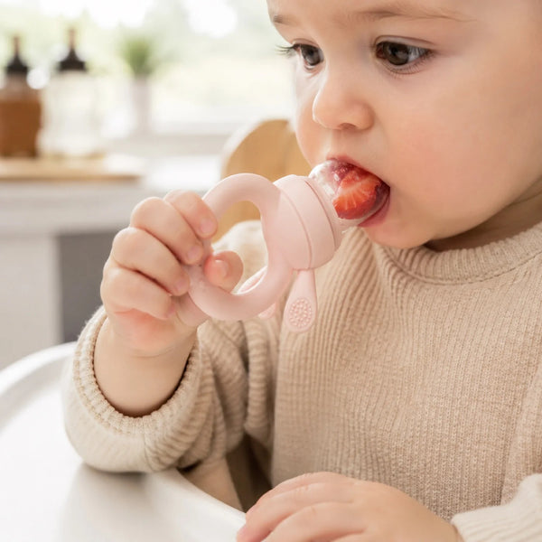 Petites mains attrapant un morceau de fruit avec la grignoteuse en silicone