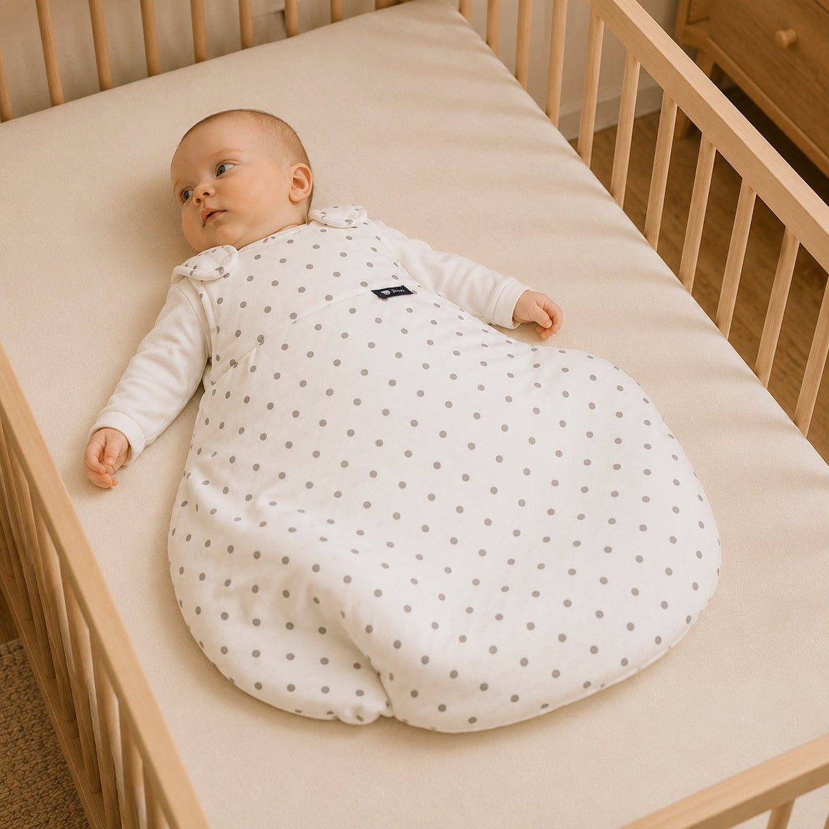 Bébé éveillé et détendu dans sa gigoteuse TOG, allongé sur le dos dans son lit