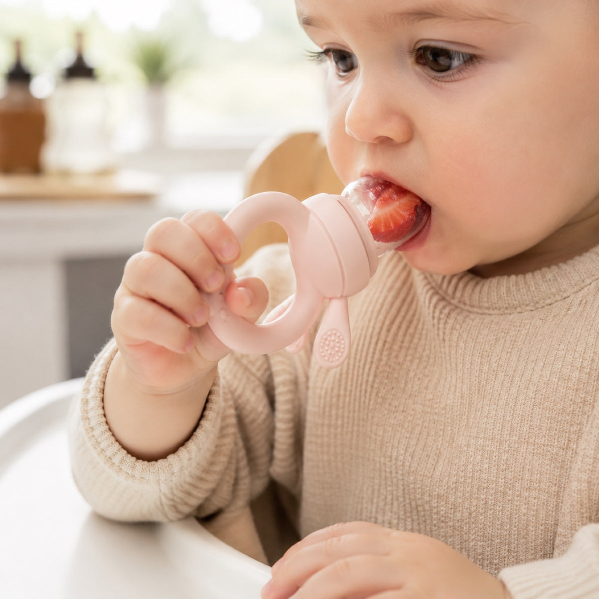 Bébé savoure une fraise avec la grignoteuse en silicone Haakaa